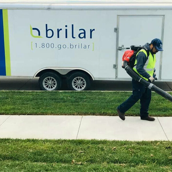 Photo of Brilar employee blowing leaves off sidewalk